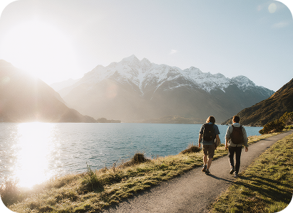Couple walking on path beside lake with mountains in background